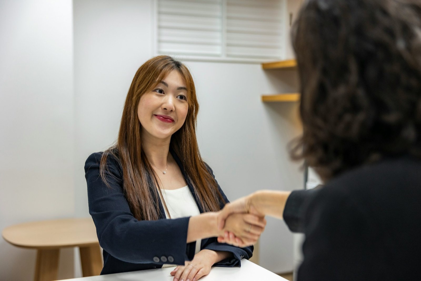 a woman shaking hands with another woman at a table